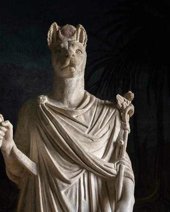 Marble statue of Anubis with the head of a jackal, robed and holding a staff.
